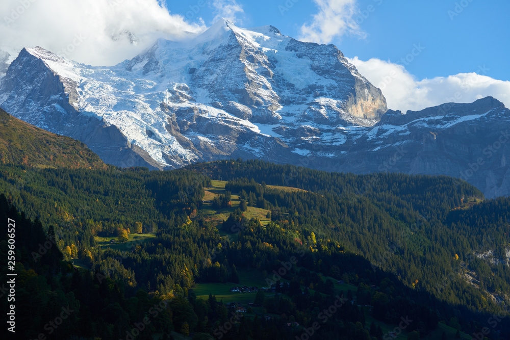 High mountains peaks in clouds above Swiss Alpine village Wengen at sunset.