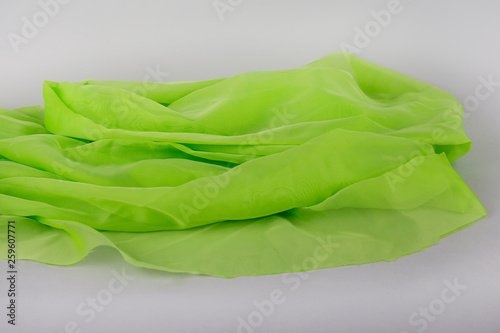 Green fabric on a gray background. Silk fabric. green background thin green fabric. silk textures in satin or velvet. Emerald or green silk background
