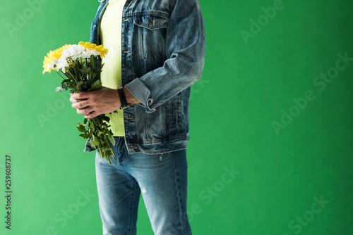cropped view of stylish mixed race man holding flowers on green screen with copy space