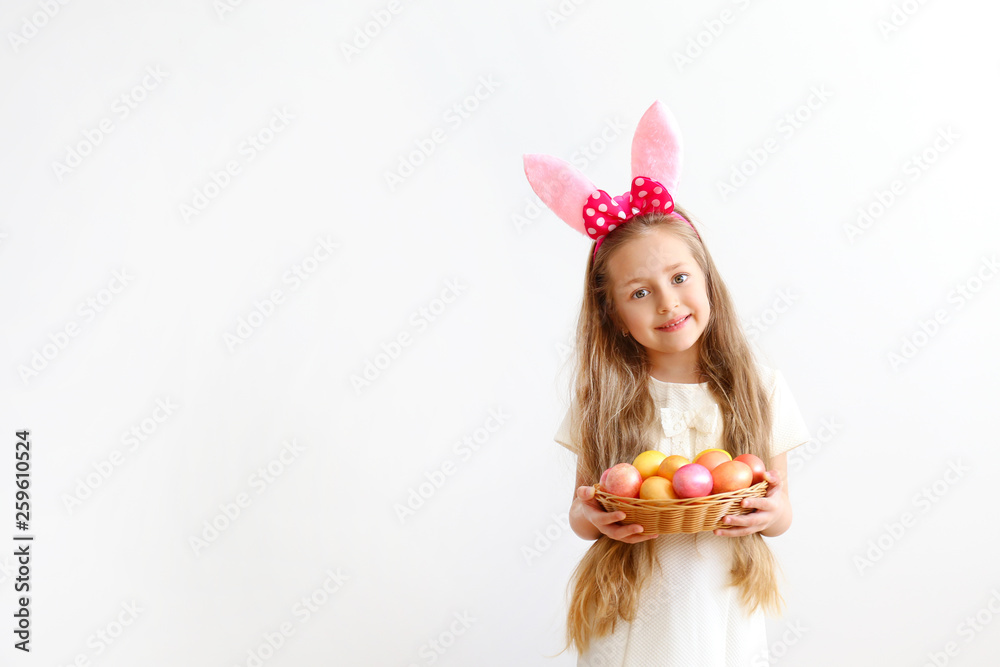 Portrait of cute little five year old girl with long blond hair wearing easter bunny ears with pink polka dot bow, smiling and having fun on holy day. Isolated white backgroung, copy space, close up.