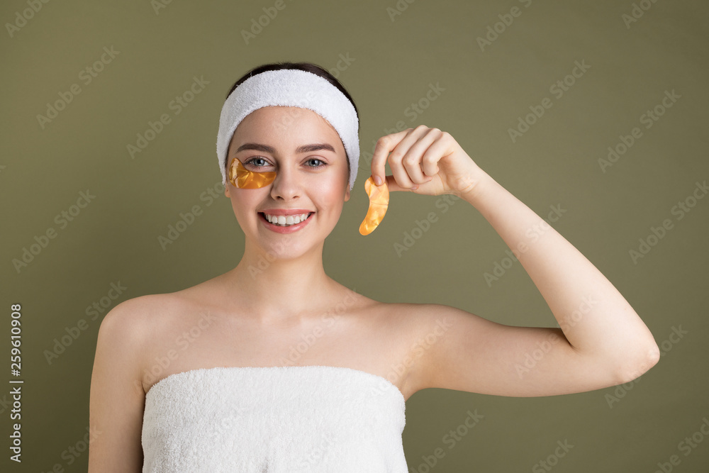 Happy smiling young girl takes care of herself, under the eye of silicone patches from swelling Happy smiling young girl takes care of herself, under the eye of silicone patches from swelling