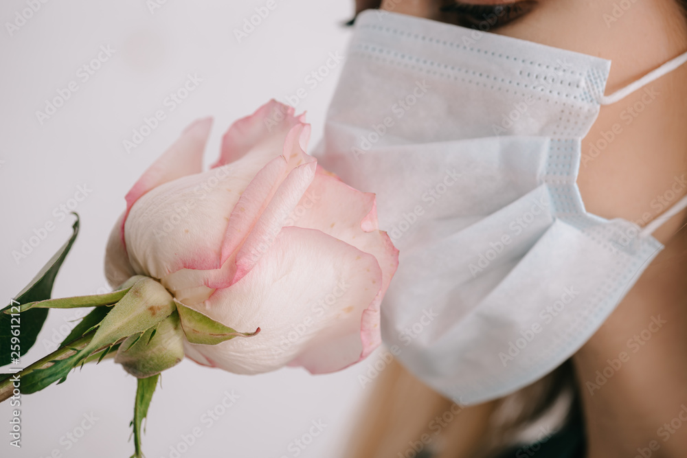 cropped view of woman in medical mask smelling rose cropped view of woman in medical mask smelling rose