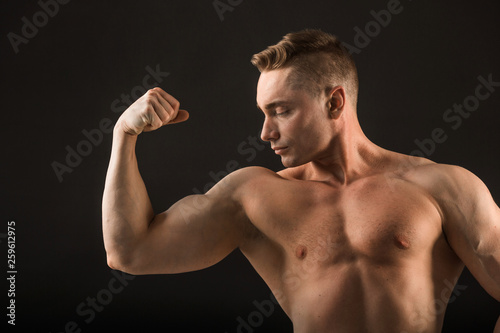 handsome muscular man on black background showing biceps