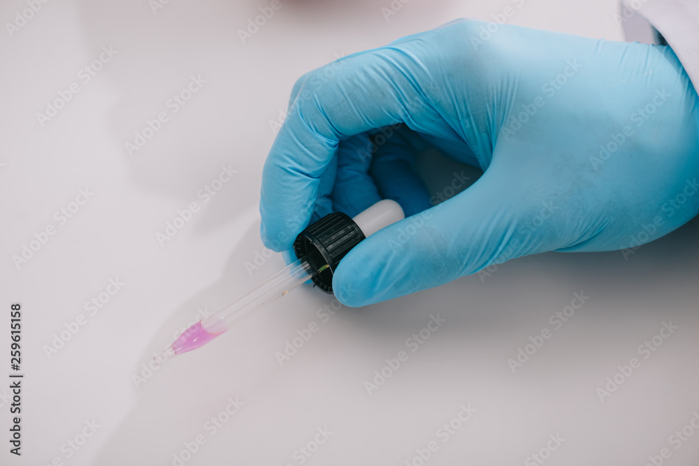 cropped view of doctor in latex glove holding pipette with liquid cropped view of doctor in latex glove holding pipette with liquid