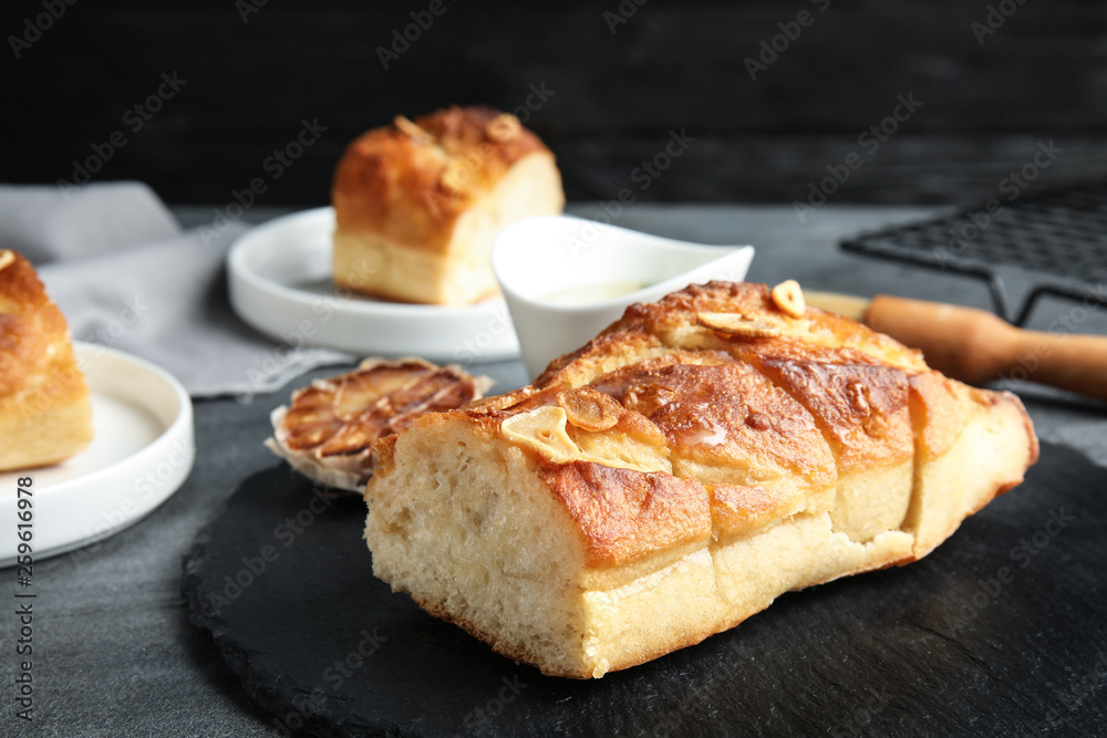 Slate plate with homemade garlic bread on table. Space for text Slate plate with homemade garlic bread on table. Space for text