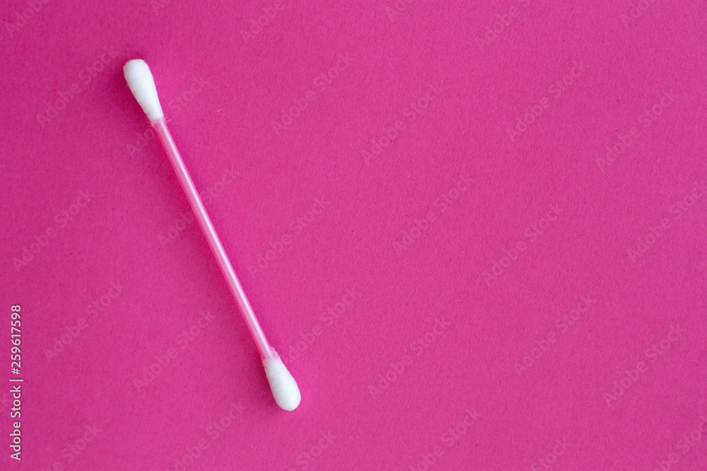 pink cotton buds with white heads laid out on a pink background