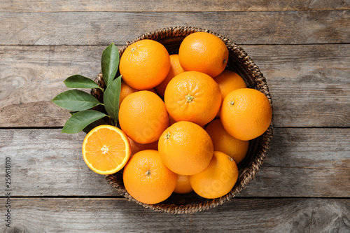 Fototapeta Naklejka Na Ścianę i Meble -  Wicker bowl with ripe oranges on wooden background, top view