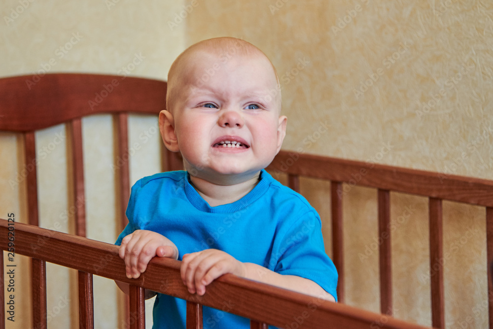 Portrait of a funny boy who grimaces in his crib Portrait of a funny boy who grimaces in his crib