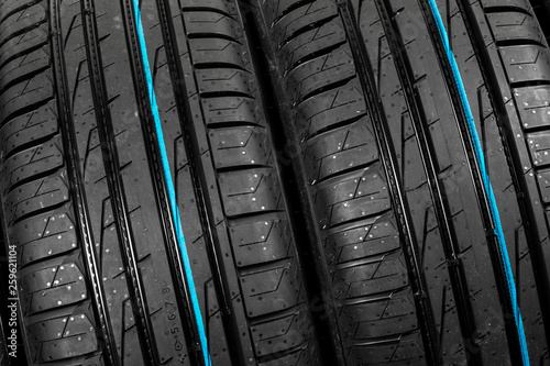 Set of summer car tires on black background. Tire stack background. Car tyre protector close up. Black rubber tire. Brand new car tires. Close up black tyre profile. Car tires in a row © Aleksei