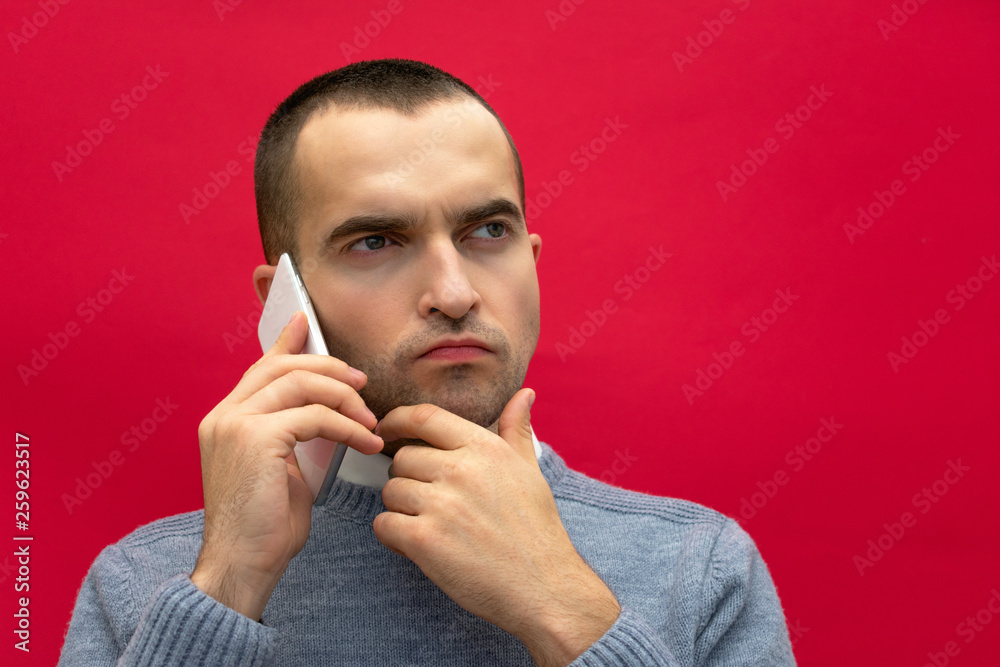 Portrait, man talking on phone, to the side looking up, front view, bright red background, close up Portrait, man talking on phone, to the side looking up, front view, bright red background, close up