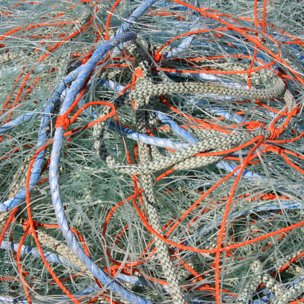 Full frame tangle of blue white and orange fishing nets in a pile
