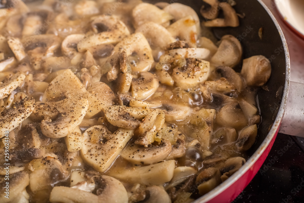 Cooking dishes from sliced mushrooms with spices. Delicious champignons in boiling broth Cooking dishes from sliced mushrooms with spices. Delicious champignons in boiling broth