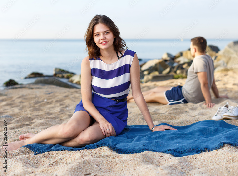 Fototapeta premium Girl sitting on the beach. Man on the background