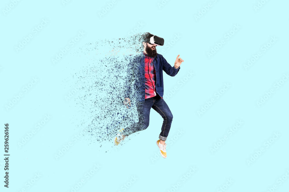Full length portrait of a jumping bearded hipster in glasses of virtual reality, man dispersing and disintegrating into particles ,concept of new technologies Full length portrait of a jumping bearded hipster in glasses of virtual reality, man dispersing and disintegrating into particles ,concept of new technologies