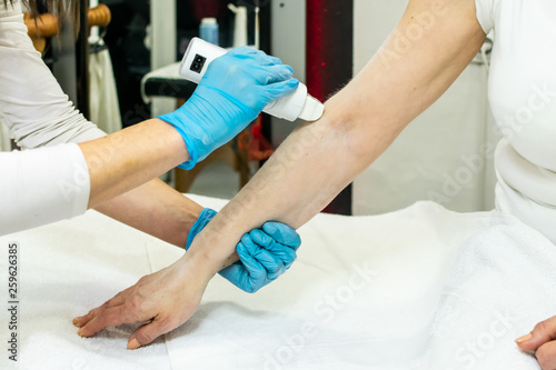 Cosmetologist applying cold wax. Process of arms depilation, waxing. Body, health care