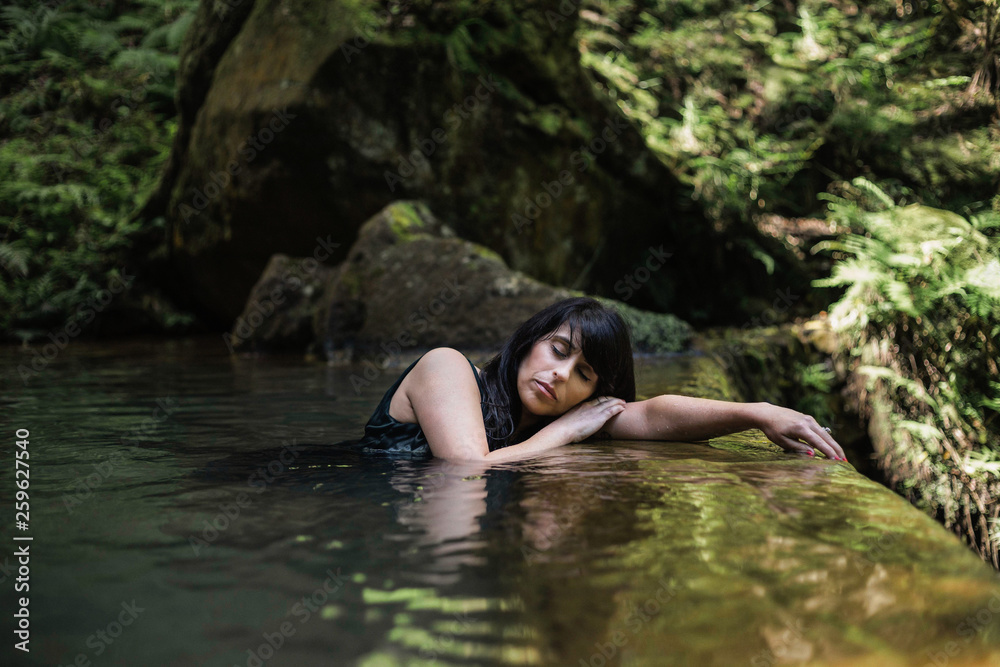 Beautiful, mature Portuguese woman relaxing in a hot spring spa in Caldeira Velha, Sao Miguel, Azores, Portugal. Beautiful, mature Portuguese woman relaxing in a hot spring spa in Caldeira Velha, Sao Miguel, Azores, Portugal.
