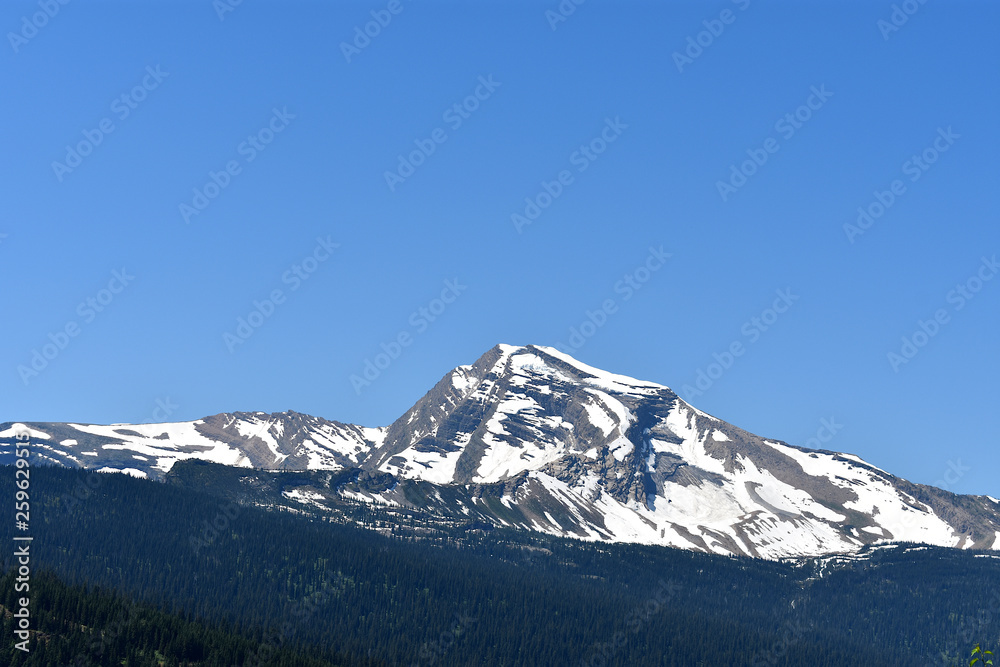 Snow Covered Mountain Peak Under a Bright Blue Sky Going-to-the-Sun Road, Glacier National Park, Montana Snow Covered Mountain Peak Under a Bright Blue Sky Going-to-the-Sun Road, Glacier National Park, Montana