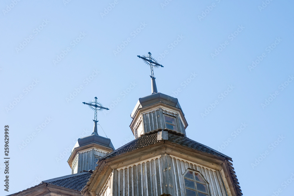 Wooden Cross Background. Wooden cross on a simple steeple set against a blue sky. Church Roof with a cross. Church building roof with holy cross