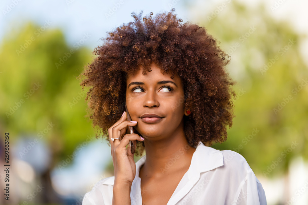 Outdoor portrait of a Young black African American young woman speaking on mobile phone Outdoor portrait of a Young black African American young woman speaking on mobile phone
