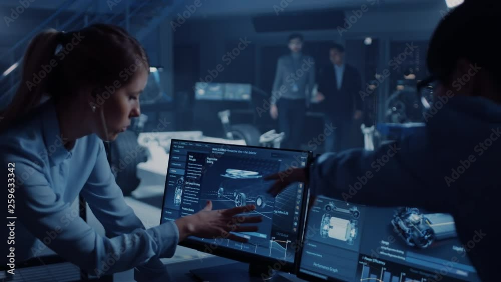 Female and Male Engineers are Discussing the 3D CAD Software Render of an Electric Concet Car. High Tech Laboratory with a Prototype Vehicle Chassis. Female and Male Engineers are Discussing the 3D CAD Software Render of an Electric Concet Car. High Tech Laboratory with a Prototype Vehicle Chassis.