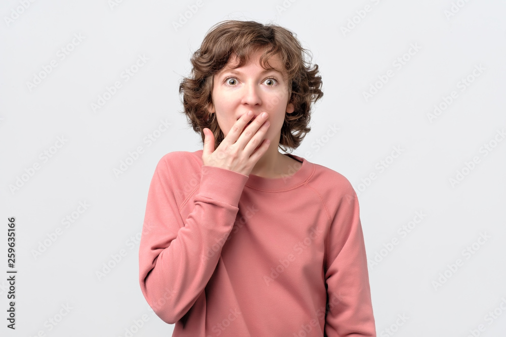 woman looking at camera covering mouth with hands in disbelief. woman looking at camera covering mouth with hands in disbelief.