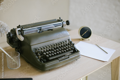desktop, retro typewriter. Antique typewriter on a wooden table background with papers . office equipment. clock, pencil, flowers