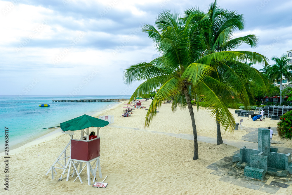 Tropical Caribbean island beach scene. Life guard tower, coconut palm trees, white sand.