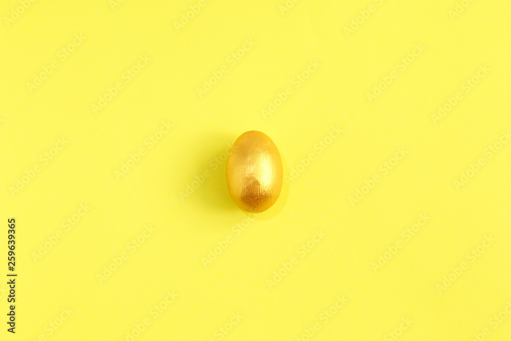 Golden egg, a symbol of making money and successful investment on yellow background. Minimal Happy Easter concept. Golden egg, a symbol of making money and successful investment on yellow background. Minimal Happy Easter concept.