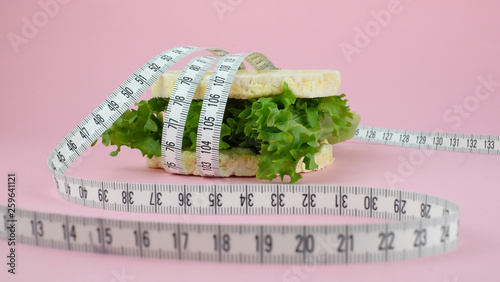  burger from lettuce for a diet on a pink background. Weight loss and tape measure.