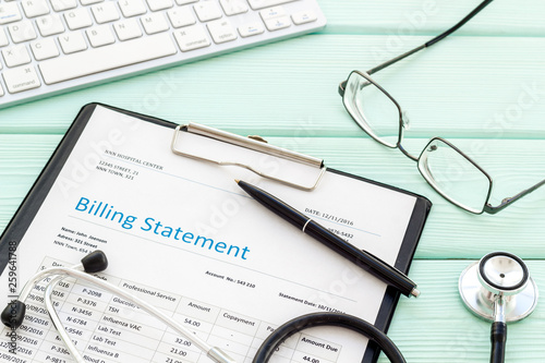 phonendoscope  billing statement and keyboard on work desk of doctor in hospital mint green background