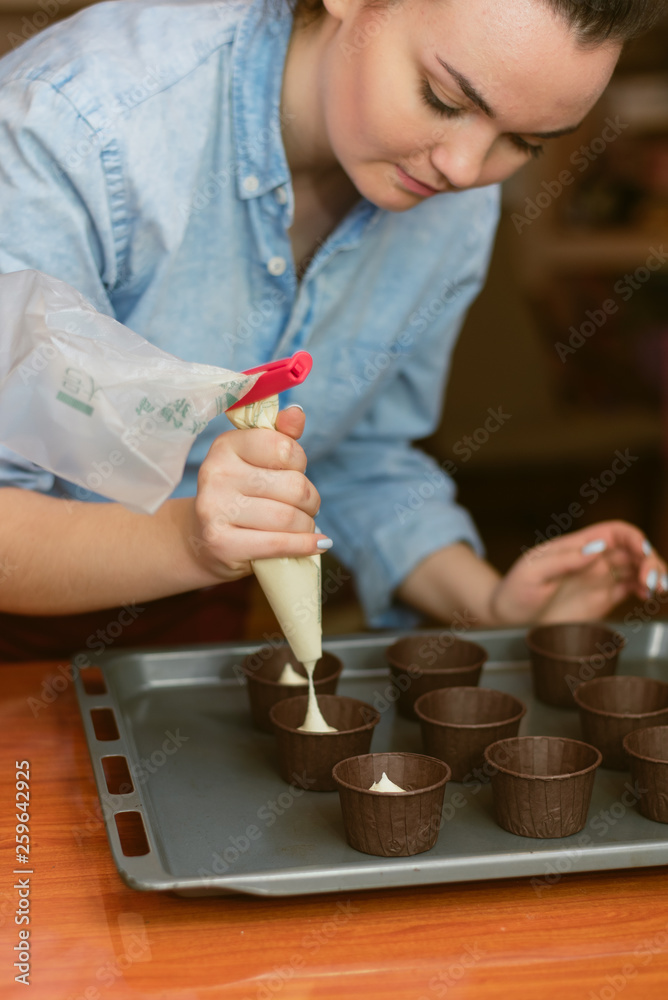 pastry chef makes muffins and pours dough into molds pastry chef makes muffins and pours dough into molds