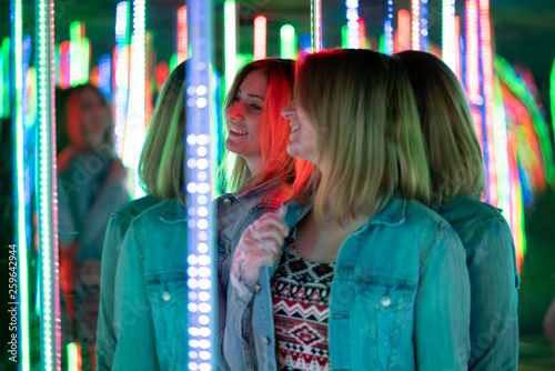 Obraz na plátně sweet caucasian girl walks in a mirror maze with colorful diodes and enjoys an u