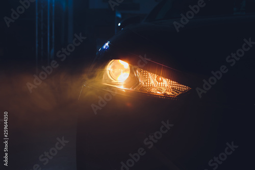 Obraz na plátně In the automobile salon garage, center the headlights of the car are very close, turning on turning off checking the front light dimensions