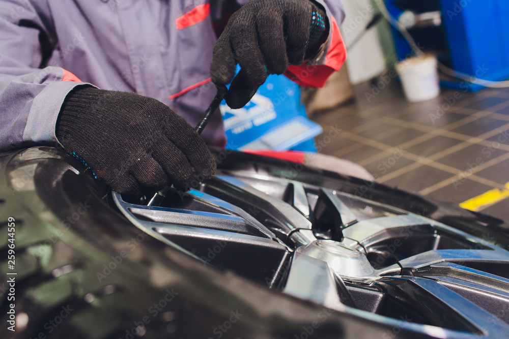 repairman balances the wheel and installs the tubeless tire of the car