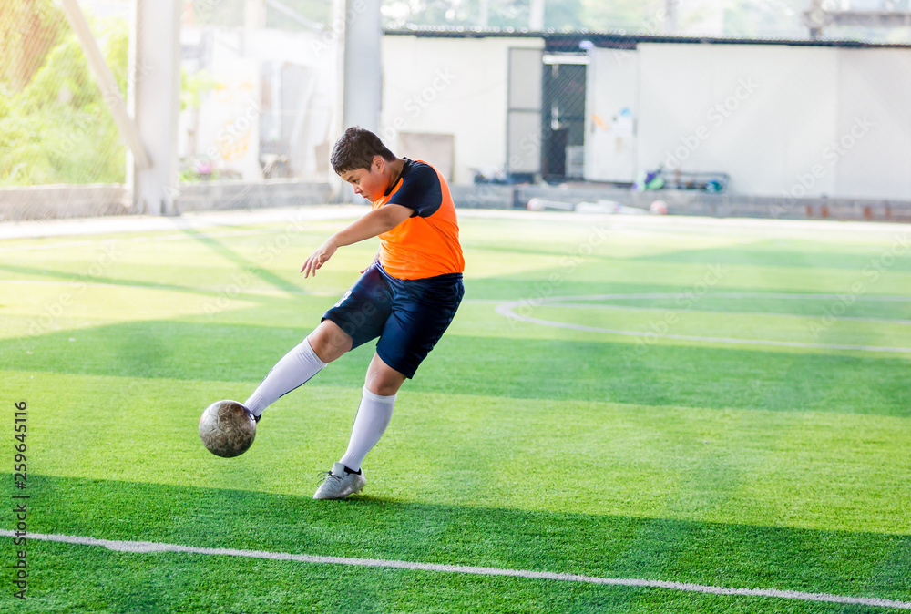 The Asian kid soccer player shoot bounce ball at  to goal on artificial turf to goal