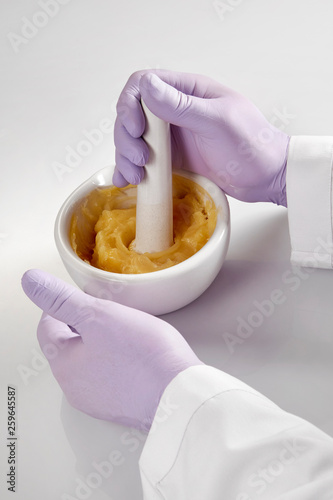 Closeup of the hands of a pharmacist or scientist, holding a mortar and pestle and wearing rubber gloves,pharmacist mixing medicine