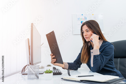Female office worker making a phone call while sitting at her desk