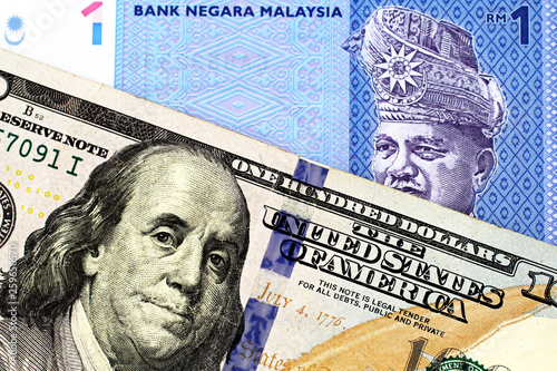 A blue one ringgit bank note from Malaysia with an American one hundred dollar bill in macro