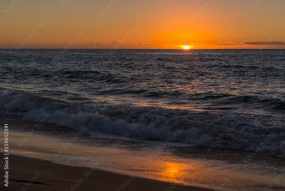 Orange sunset over ocean and sand with reflections Orange sunset over ocean and sand with reflections