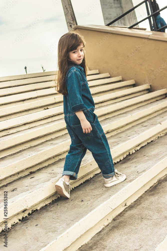 Little girl in denim walking across the stairs
