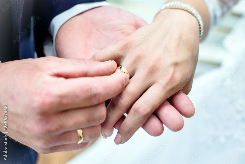 The groom puts a wedding ring on the bride's finger The groom puts a wedding ring on the bride's finger