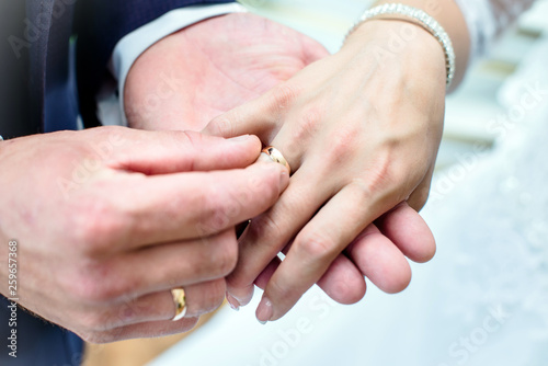 The groom puts a wedding ring on the bride's finger