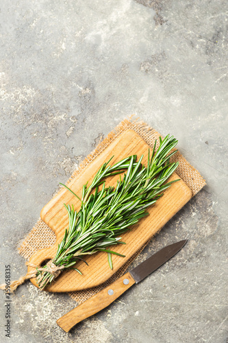 A pile of fresh fragrant rosemary on a cutting board gray concrete background. Copy space. View from above. Flat lay.