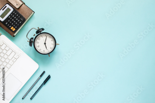 Creative flat lay of workspace desk with laptop,  caculator and notebook on blue colour background.  Business, Insurance or money concept
