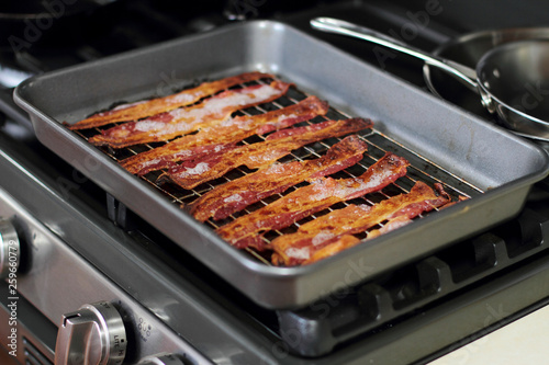 Cooked bacon in a baking tray out of the oven.