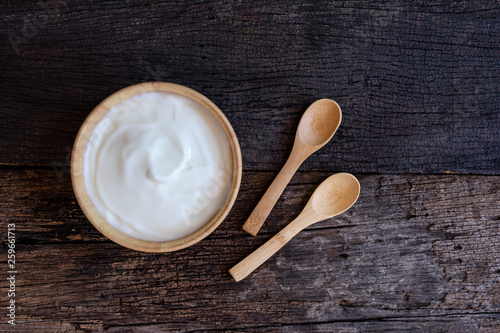 Natural homemade plain organic yogurt in wood bowl on wood texture background