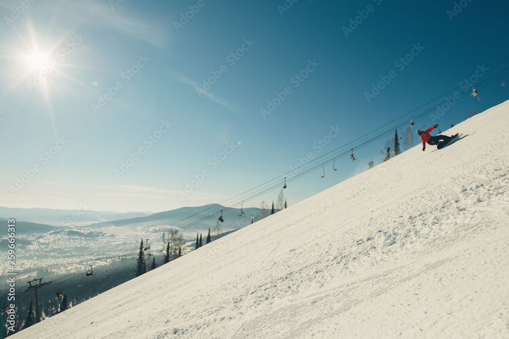 Snowboarder moving on mountain slop in sunny winter day