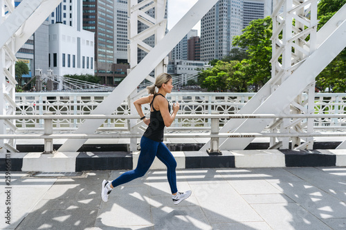 Photography Young asian woman runner running on city bridge road