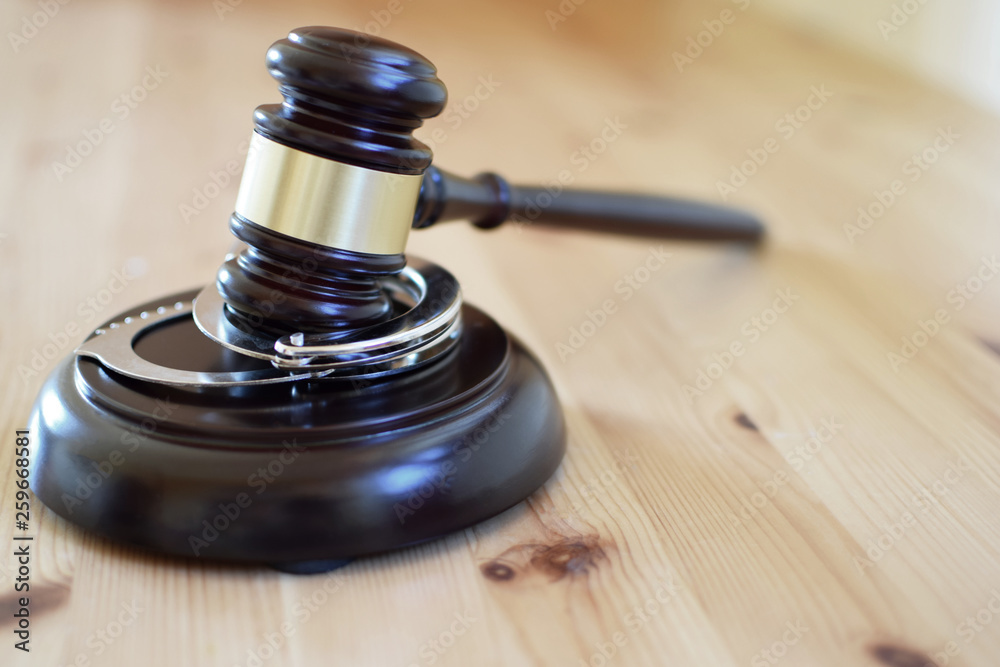 Judges gavel or law mallet and handcuffs on wooden background. Judgement, legal system and time for justice concept.