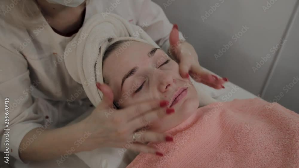 A professional cosmetologist does a face massage procedure before applying a mask. New concept in cosmetology. A professional cosmetologist does a face massage procedure before applying a mask. New concept in cosmetology.